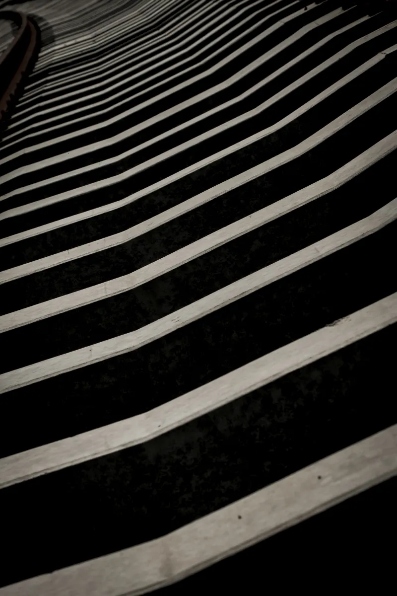 Wavy white pavement stripes bending across a black ground